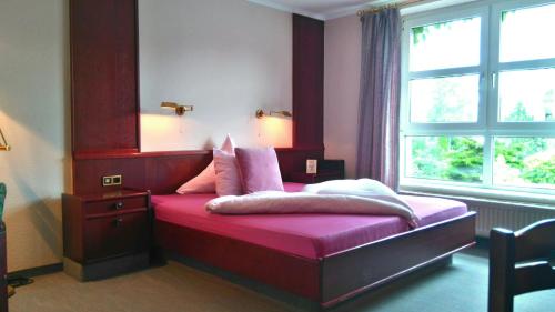 a bedroom with a bed with pink sheets and a window at Hotel am Hasengarten in Bad Bederkesa