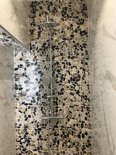 a shower in a bathroom with a wall of rocks at Ria Studios in Olhão
