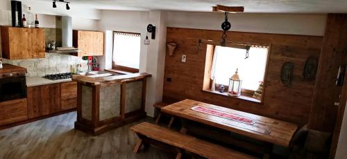 a kitchen with wooden walls and a table and windows at Durmi e Insumiasci in Forni Avoltri