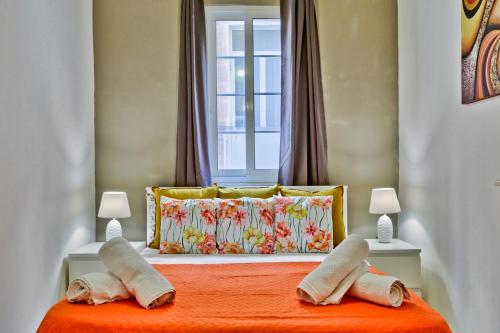 Un dormitorio con una cama con dos almohadas y una ventana. en Charming Valletta 1 bedroom apartment off Republic Street sleeps 4, en La Valeta