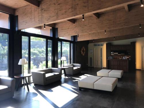 una sala de estar con muebles blancos y ventanas grandes. en Firriato Hospitality Cavanera Etnea Resort & Wine Experience, en Castiglione di Sicilia