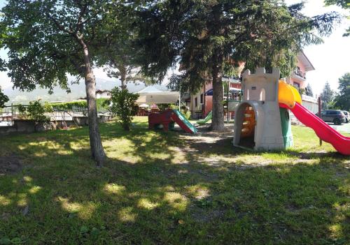 a playground with a slide in a yard at Hotel Cristina in Verrayes