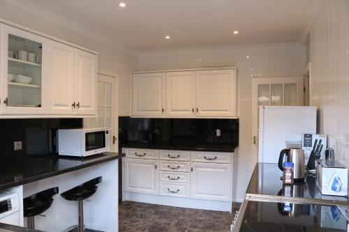 una cucina con armadi bianchi e piano di lavoro nero di Goldcrest Cottage a Sandown
