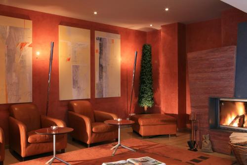 a waiting room with chairs and a fireplace at Hotel Evviva in Oberstaufen