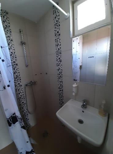 a white bathroom with a sink and a shower at Fortuna Apartmanházak in Bogács
