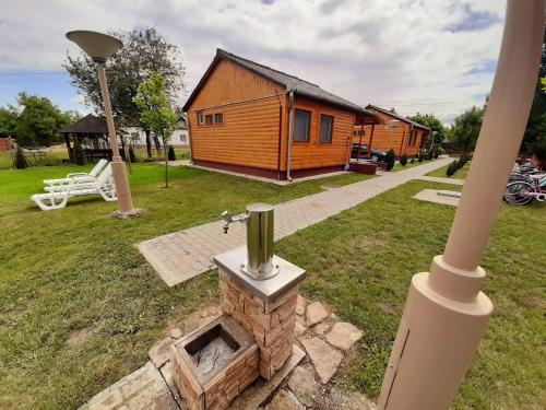 a log cabin with a brick fireplace in a yard at Fortuna Apartmanházak in Bogács