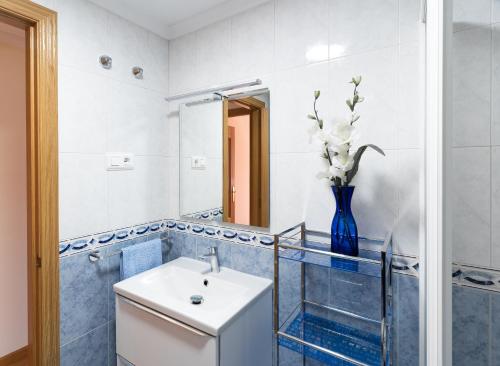 een badkamer met een wastafel en een vaas met bloemen erin bij Housingleón - Parque de las Artes con Garaje in León