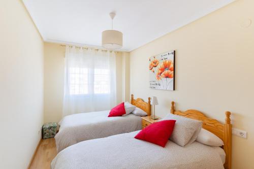 een slaapkamer met 2 bedden en rode kussens bij Housingleón - Parque de las Artes con Garaje in León