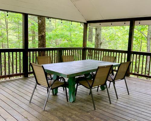a wooden deck with a table and chairs on a porch at Barefoot Hills in Dahlonega