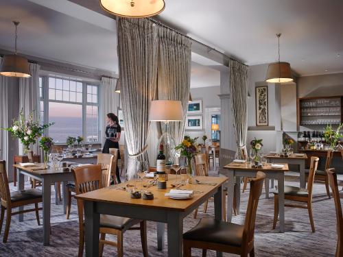 um restaurante com mesas e cadeiras e uma mulher ao fundo em Dunmore House Hotel em Clonakilty