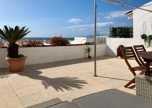 een patio met een tafel en stoelen en de oceaan bij Sunset Los Lances - Tarifa in Tarifa