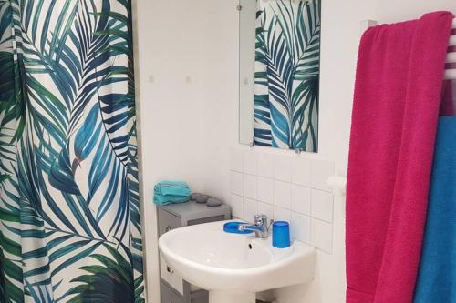 a bathroom with a sink and a pink shower curtain at Proche de la plage, très bien situé in Ondres