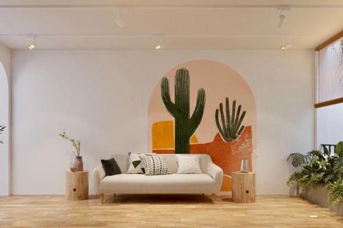 un salon avec un canapé et une fresque murale de cactus dans l'établissement L'amie Hotel & Studio, à Đà Lạt