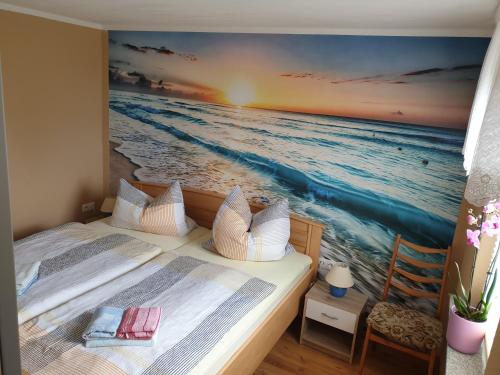 a bedroom with two beds and a painting of the ocean at Ferienhaus Scheffler in Saal
