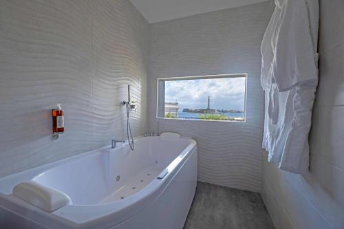 bagno bianco con vasca e finestra di Miti Dello Stretto B&B a Messina