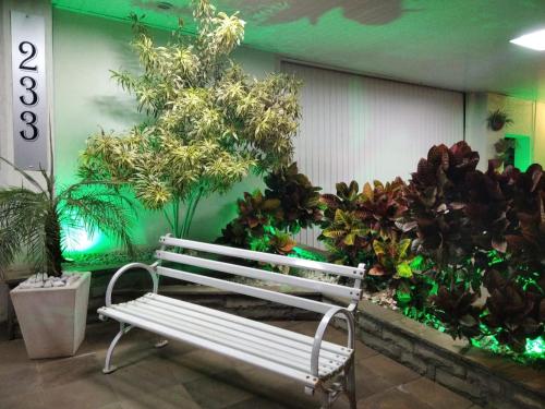 a white bench in a room with plants at Germanias Blumen Hotel in Passo Fundo