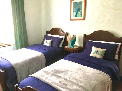 a bedroom with two beds with blue and white sheets at Le Figuier in La Forêt-Auvray