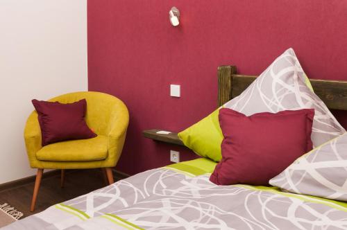a bedroom with a bed and a yellow chair at Pension SiLa in Groß-Umstadt
