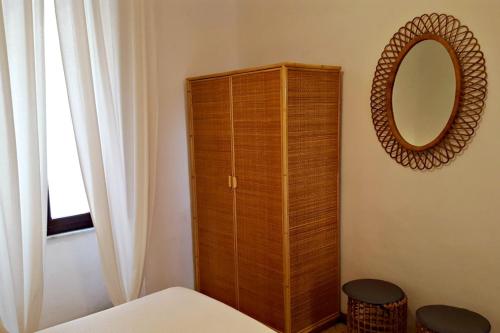 a bedroom with a wooden cabinet and a mirror at Case vacanza Barbatoja in Fetovaia