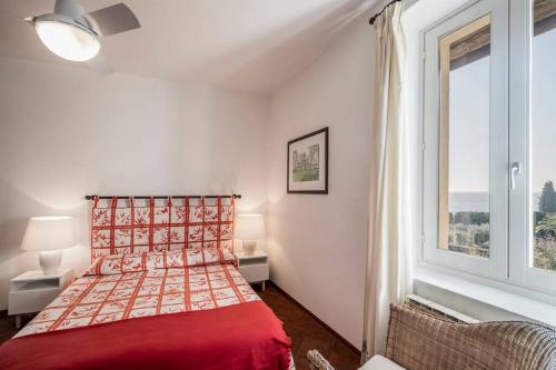 a bedroom with a red bed and a window at Uliveto - Apartment in olive grove directly on the lake in Gargnano