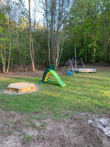 a playground with a green slide and a swing at Skogshöjda in Tjörnarp