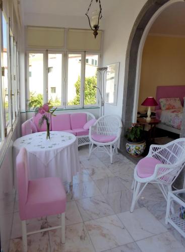 a living room with pink chairs and a table at Villa Erika Madeira in Caniço