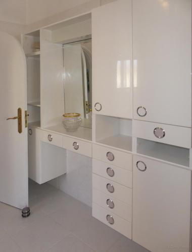 a white dressing room with white cabinets and a mirror at Villa Erika Madeira in Caniço