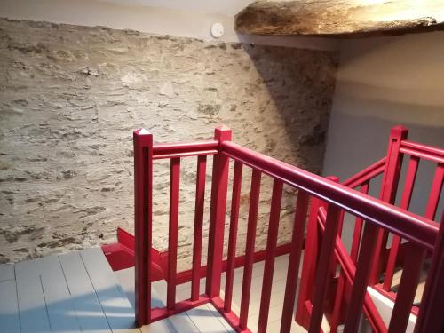 a staircase with a red railing in a room with a stone wall at La Gaucherie aux Dames in Vihiers