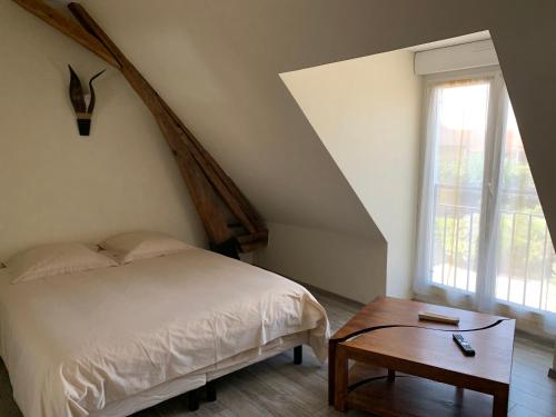 a bedroom with a bed and a table and a window at Domaine d'Auxonnettes Chambres d'Hôtes et Gîtes in Saint-Fargeau-Ponthierry