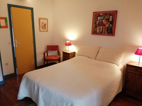 a bedroom with a white bed and a chair at La Gaucherie aux Dames in Vihiers