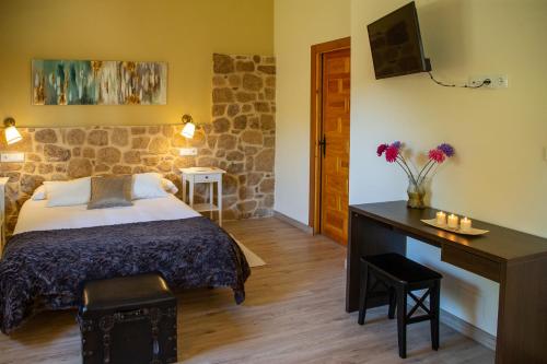 Un dormitorio con una cama y un escritorio con flores. en Hotel Rural El Tejar de Miro en Ceadea