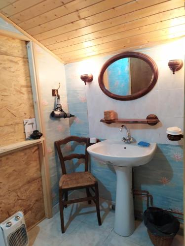 une salle de bain avec un lavabo, un miroir et une chaise dans l'établissement CHARDON BLEU Appartement chambre cuisine coin à manger sanitaires salle d'eau, à Barcelonnette