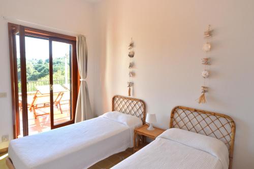 two beds in a room with a balcony at Case vacanza Barbatoja in Fetovaia