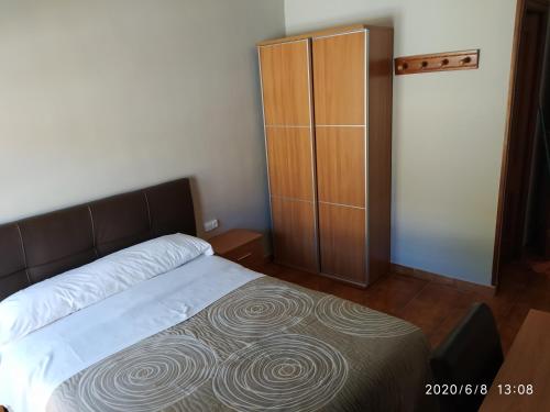 a bedroom with a bed and a wooden cabinet at Hotel Europa in Tomelloso
