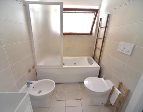 a bathroom with a tub and a toilet and a sink at Case vacanza Barbatoja in Fetovaia