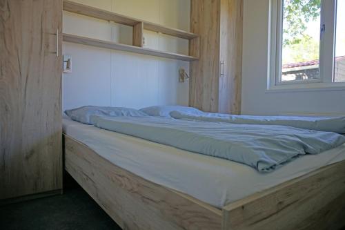 a bed with blue pillows on it next to a window at Minicamping In de Bocht in Grijpskerke