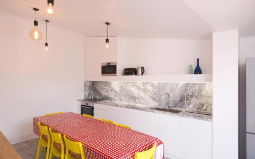 a kitchen with a red and white table and yellow chairs at Margueda in Alcains
