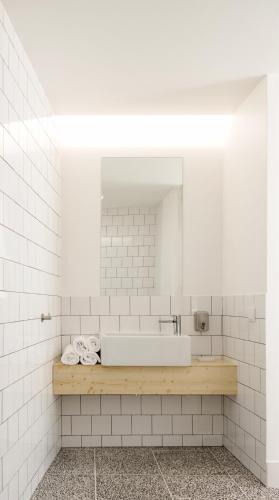 a white tiled bathroom with a tub and a mirror at Margueda in Alcains