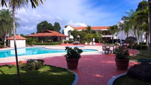 ośrodek z basenem i palmami w obiekcie Los Corozos Apartment A2 Guavaberry Golf and Country Club w mieście Juan Dolio