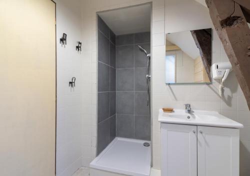 a white bathroom with a shower and a sink at La Ferme de Couty in Saint-Pé-de-Bigorre