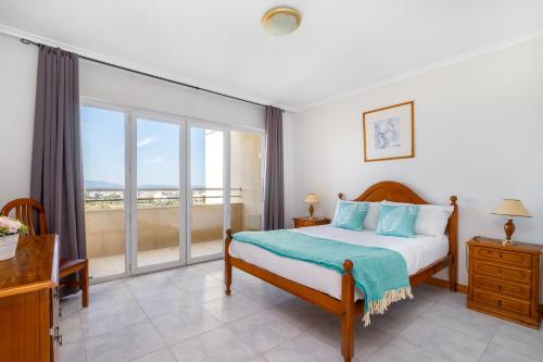 Un dormitorio con una cama y un balcón. en Jardins da Rocha BeachView by Encantos do Algarve 19A, en Portimão
