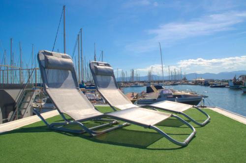 two chairs sitting on a dock with boats in the water at HouseBoat Cagliari in Cagliari