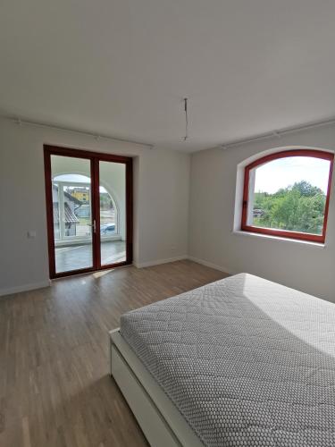 a white room with a bed and two windows at Saulėlydžio apartamentai in Palanga