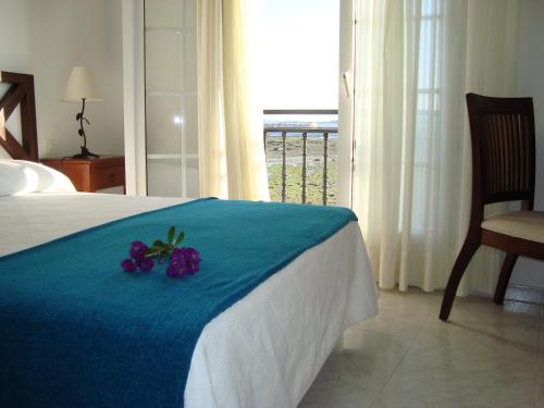 a bed with a blue blanket and purple flowers on it at Ribeira de Fefiñanes in Cambados