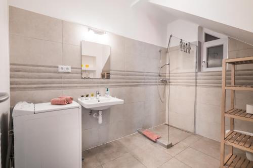 a white bathroom with a sink and a shower at Helka Ház in Siófok