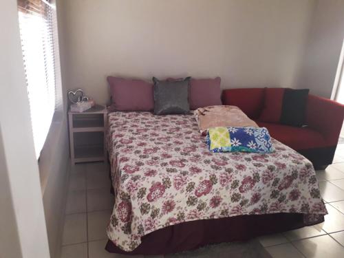 een bed met een deken en een bank in een kamer bij Mofolo Heights in Johannesburg