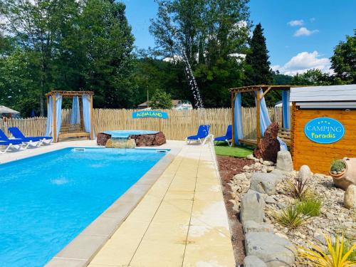 - une piscine avec des chaises bleues et une balançoire dans l'établissement CAMPING PARADIS FAMILY des ISSOUX, à Lalevade-dʼArdèche