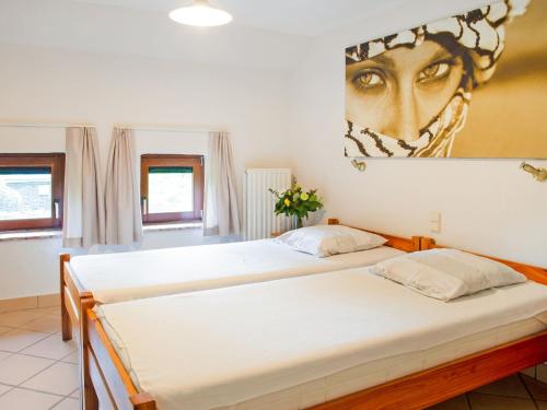 two beds in a bedroom with a painting on the wall at Lavish Holiday Home in Malmedy with Sauna in Longfaye
