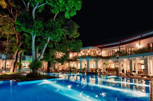 a swimming pool in front of a building at night at Mahaweli Reach Hotel in Kandy
