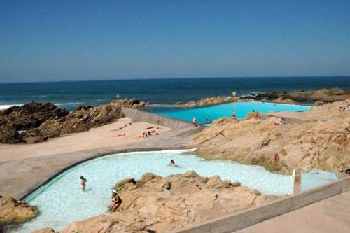 two swimming pools on the beach with people in them at Casa do Moinho de Vento in Leça da Palmeira